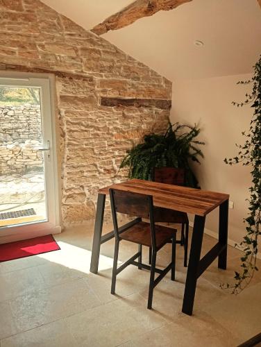 a wooden table and chair in a room with a window at Gite Romantique au coeur du Lot in Crayssac