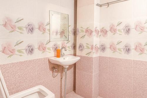 a bathroom with a sink and a shower with pink flowers at Comfort Stay - Saheed Path Ahimamau, Near Lulu Mall in Lucknow