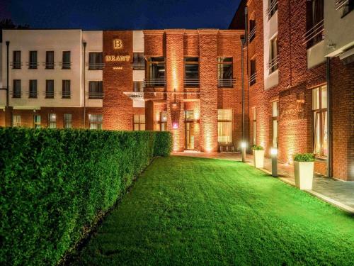a green lawn in front of a brick building at Mercure Wiazowna Brant in Wiązowna