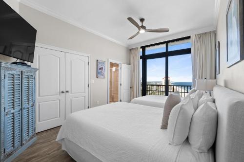 a white bedroom with two beds and a balcony at The Oasis at Orange Beach 2411 (Phoenix West II) in Orange Beach