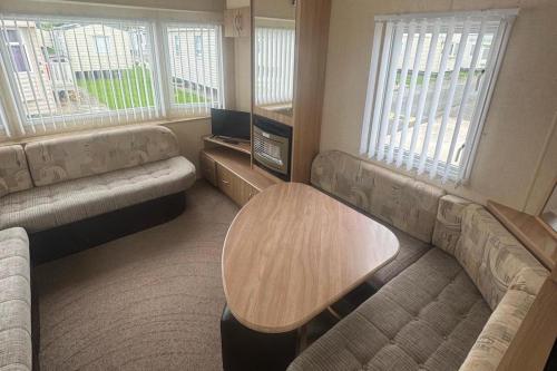 a living room with couches and a table and windows at 3 Bed Caravan - Sleeps 8 - Pets - Parking in Rhyl