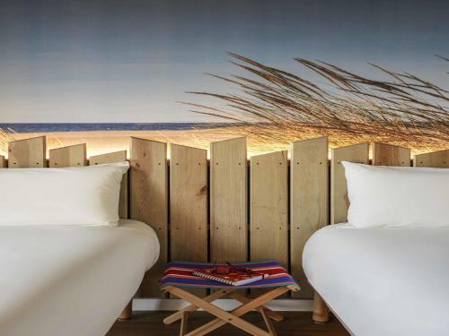 a bedroom with two beds and a wooden fence at Ibis Styles Montpellier Aéroport Parc Des Expos in Mauguio