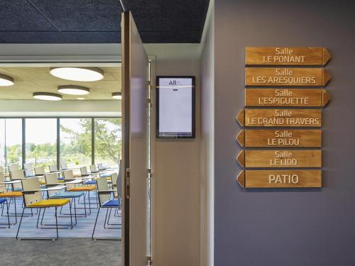 a room with tables and chairs and a sign on the wall at Ibis Styles Montpellier Aéroport Parc Des Expos in Mauguio