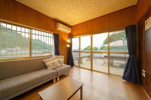 a living room with a couch and large windows at 内竈ひなた庵 in Kamegawa