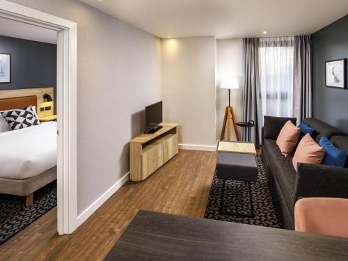 a hotel room with a bed and a couch at Aparthotel Adagio London Sutton Point in Sutton