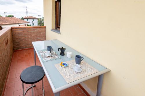 a glass table with two cups and a chair on a balcony at Cozy Corner near Lucca in Chiesina Uzzanese