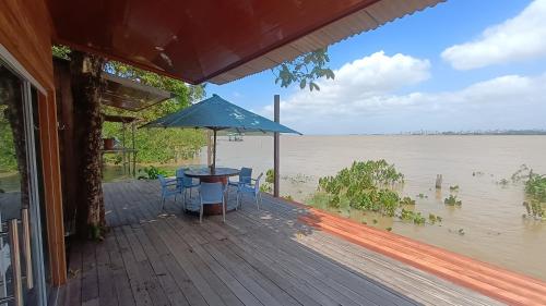 a porch with a table and chairs and an umbrella at Suíte Nefertiti ilha fantasia in Belém