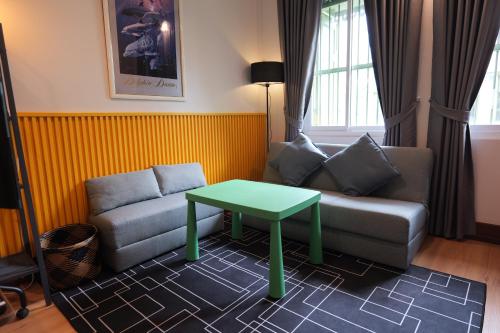 a living room with a couch and a green table at Cozy Attic Retreat Chinatown near Yaowarat - Songwat in Bangkok