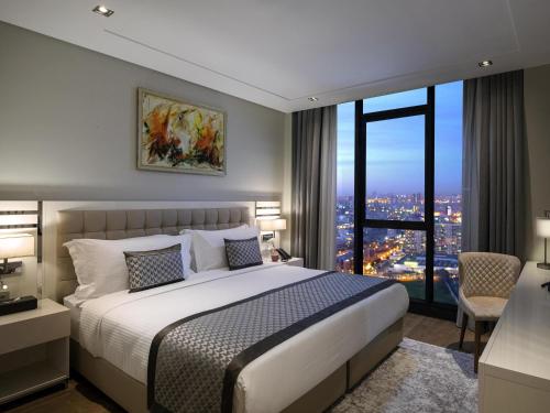 a bedroom with a large bed and a large window at Movenpick Living Istanbul West in Istanbul