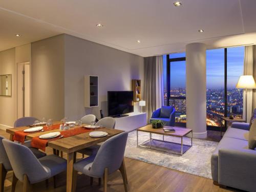 a dining room and living room with a table and chairs at Movenpick Living Istanbul West in Istanbul