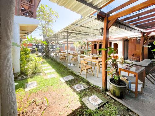 a patio with a table and chairs under a roof at RedDoorz at Villa Krisna Balangan Beach in Jimbaran