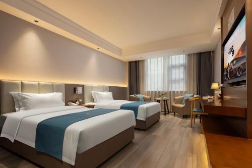 a hotel room with two beds and a television at Tongren Golden Beach Hotel in Tongren