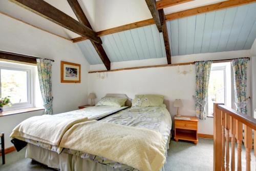 a bedroom with a bed and two windows at The Stables in Whitland