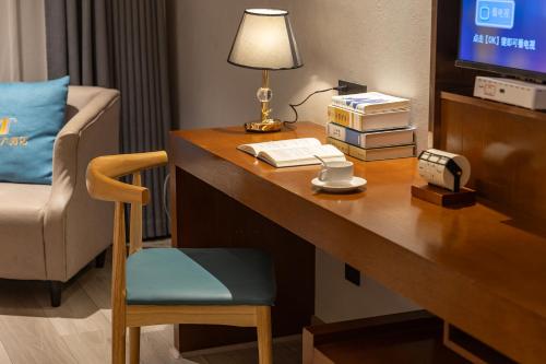 a hotel room with a desk with a lamp and a chair at Tongren Golden Beach Hotel in Tongren