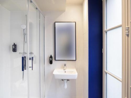 a bathroom with a sink and a mirror and a shower at ibis Styles Paris Opera Lafayette in Paris