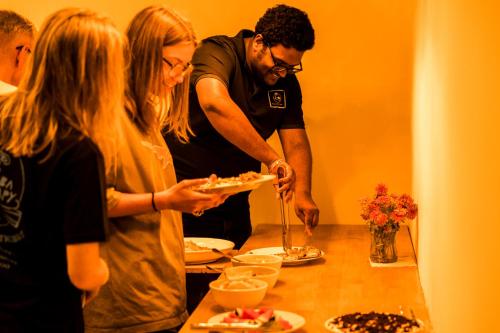 a group of people standing around a table eating food at Tropical Escape Inn in Hangnaameedhoo