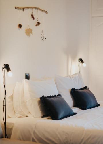 a white bed with two black pillows and two lamps at Orias Guesthouse & Farm in Kalavrita