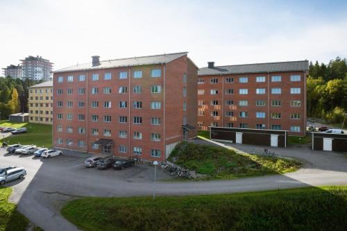 a large brick building with cars parked in a parking lot at Guestly Homes - Nordic Studio in Luleå