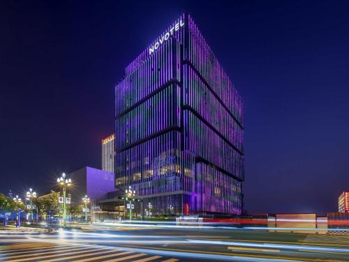 a tall building with purple lights on it at night at Novotel Xian Xixian in Xi'an