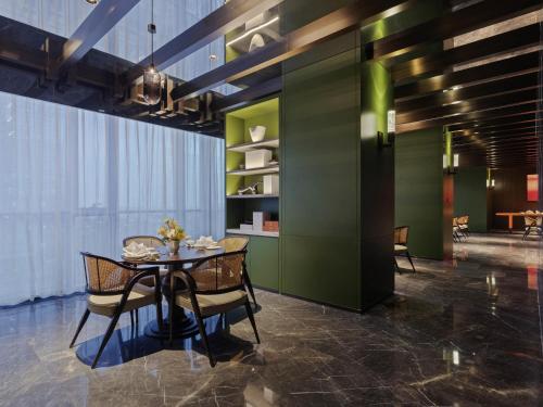 a dining room with green walls and a table and chairs at Novotel Xian Xixian in Xi'an