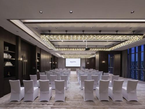 a conference room with white chairs and a projection screen at Novotel Xian Xixian in Xi'an