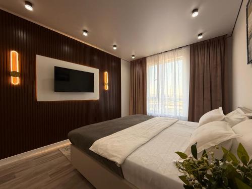 a bedroom with a bed and a tv on a wall at Классика Rayimbek 15-32, 1br in the centre & питьевая вода в подарок in Almaty
