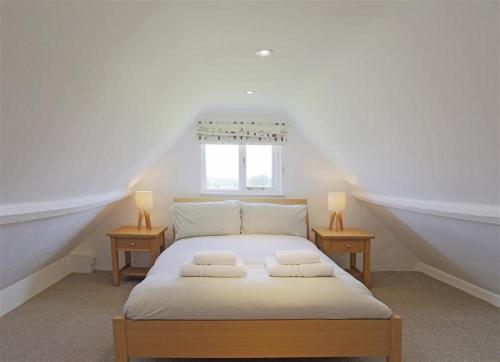 WangfordKings Farm的一间白色的卧室，里面有一张床，配有两个床头柜和一扇窗户