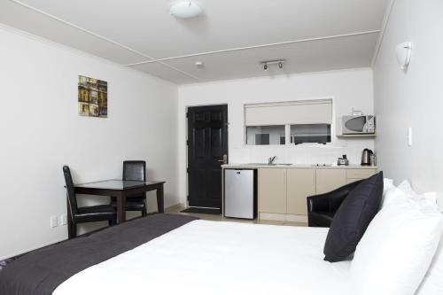 a bedroom with a white bed and a kitchen at Hygate Motor Lodge in Hamilton