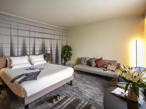 a bedroom with a large bed and a couch at Novotel Cambridge North in Cambridge