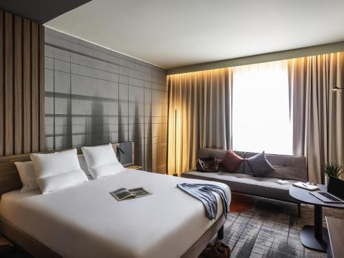 a hotel room with a large bed and a couch at Novotel Cambridge North in Cambridge