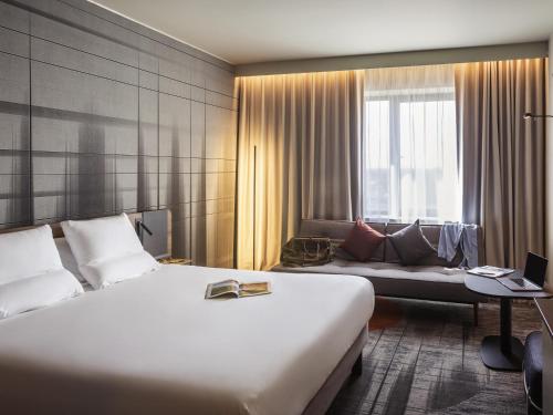 a hotel room with a large bed and a couch at Novotel Cambridge North in Cambridge
