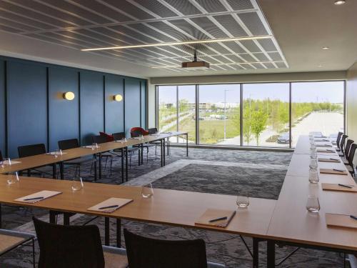 a conference room with tables and chairs and a large window at Novotel Cambridge North in Cambridge