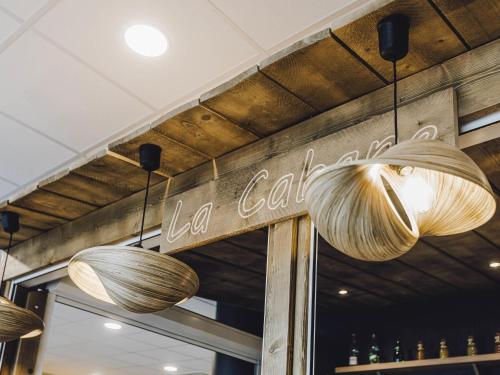 a restaurant with three lights hanging from the ceiling at ibis Styles Contres-Cheverny in Le Controis En Sologne