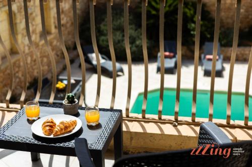 a table with a plate of food and two glasses of orange juice at Gozo Farmhouse Escape with Rustic Charm & Pool in Sannat