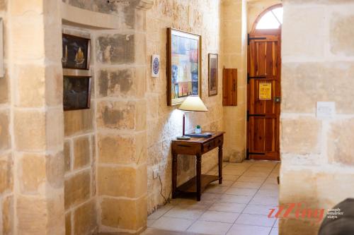 a room with a stone wall and a table with a lamp at Gozo Farmhouse Escape with Rustic Charm & Pool in Sannat