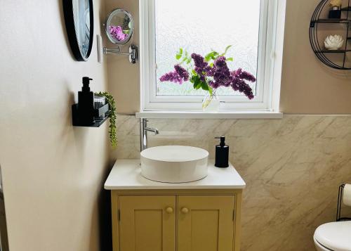 a bathroom with a sink and a window with flowers at Atte Combe Cottage in Acomb