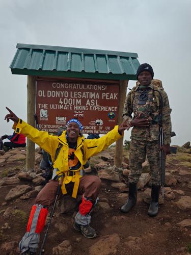 two men are standing in front of a sign at Juniper Park Resort in Nyahururu