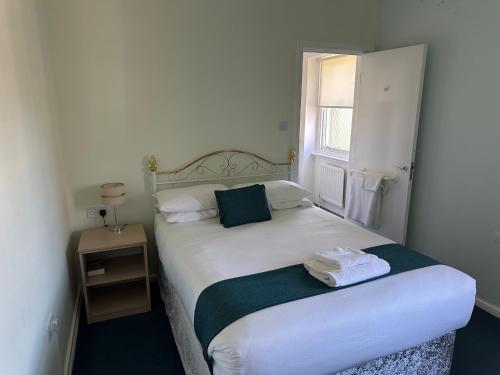 a small bedroom with a white bed with a window at Hinsley Hall in Leeds