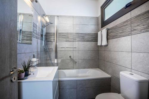 パラリムニにあるChris Le Mare Luxury Villaの浴槽、洗面台、トイレを備えたバスルーム