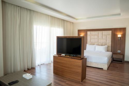 a hotel room with a bed and a flat screen tv at Rivoli Suites in Hurghada
