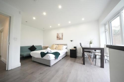 a white bedroom with a bed and a table at The Hatton Rooms in New Bedfont