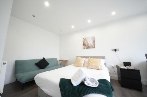 a bedroom with a bed and a blue couch at The Hatton Rooms in New Bedfont