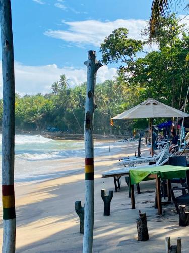 a beach with tables and umbrellas and the ocean at Lake View Villa - Tangalle in Tangalle