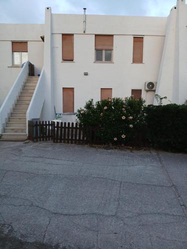a white building with stairs and flowers in front of it at Vista mare in Calasetta