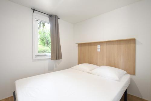 une chambre avec un lit blanc et une fenêtre dans l'établissement Camping International, à Calvi