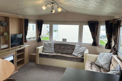 a living room with a couch and a tv at 3 Bedroom Caravan - Sleeps 6 Pool & Garden in Rhyl