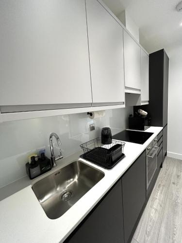 a kitchen with white cabinets and a stainless steel sink at 5 Aviv Place in Addlestone