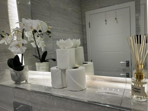 a counter with three white towels and flowers on it at 5 Aviv Place in Addlestone