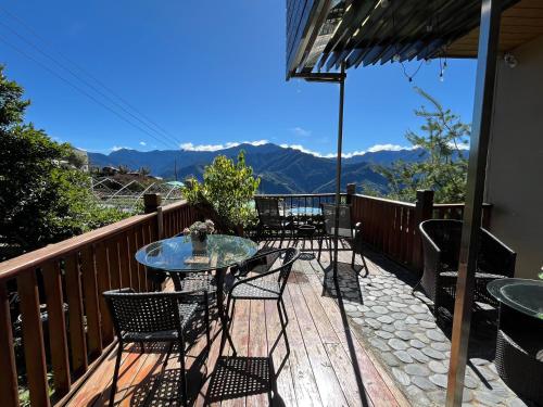 a patio with tables and chairs on a deck with mountains at Hua Mu Xing Jing B&B in Renai
