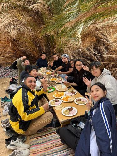 a group of people sitting around a table eating food at Alwaha safari hotel in Qasr Al Farafirah